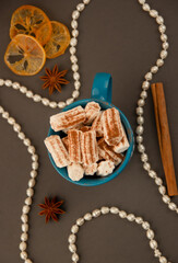 White marshmallow in a green mug with star anise and cinnamon, glare from sparkles, romantic blur.