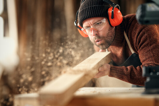 Carpenter blowing sawdust from wooden plank