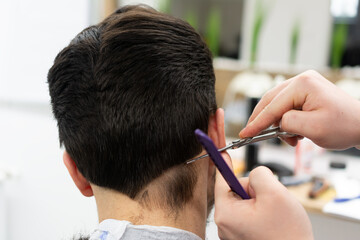 Hairdresser male hands during cutting hair with comb and scissors