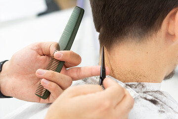 Close-up of hairdresser male hands during cutting hair