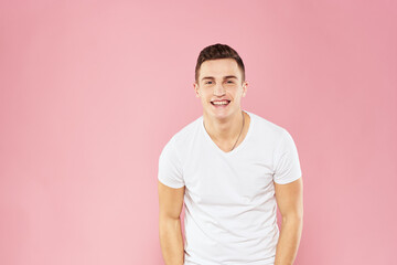 Obraz premium Cheerful handsome man in white t-shirt emotions pink isolated background