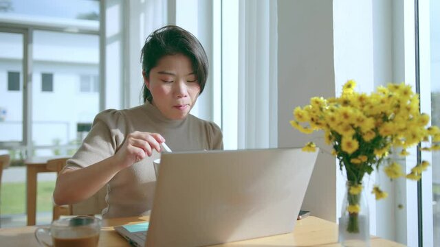 attractive asian female use laptop working online conference meeting social distancing new normal working lifestyle,asian woman working near big glass window morning time during have breakfast