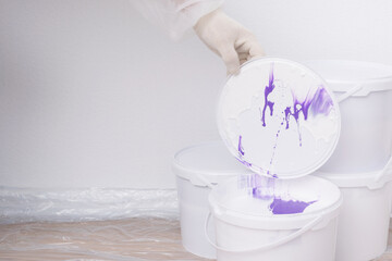 hand in a glove opens a bucket of paint, front view