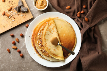 Concept of breakfast with crepes with peanut butter and nuts on gray table