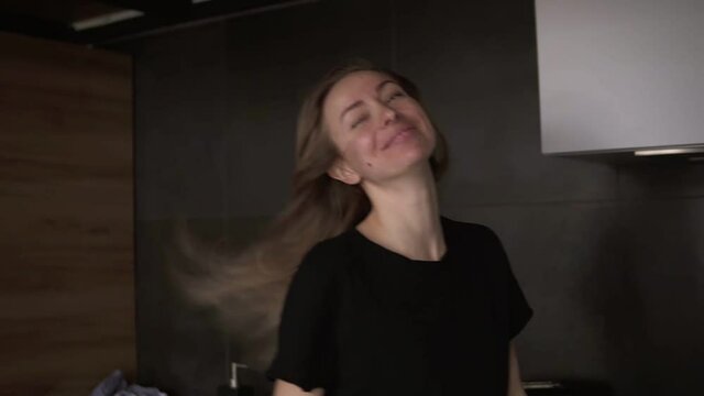 A cheerful woman with a ladle in a modern kitchen pretends to sing