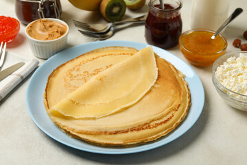 Concept of cooking breakfast with thin pancakes and ingredients on white textured background