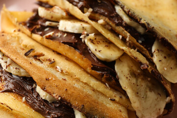 Delicious crepes with chocolate paste, banana and nuts, close up
