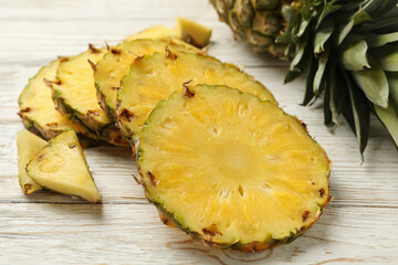 Pineapple and slices on white wooden background