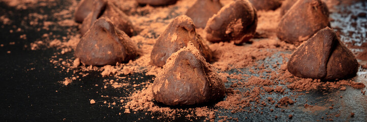 Chocolate truffles with cocoa powder panorama on a black background