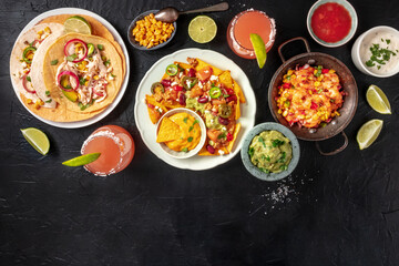 Mexican food, shot from the top with a place for text. Nachos, tacos, Paloma cocktails, and various dips