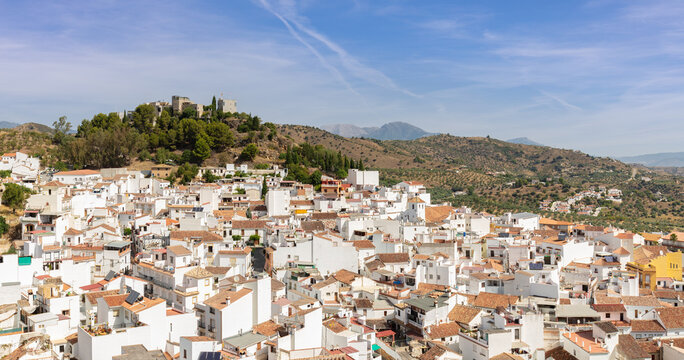 The old historic mountain village of Monda in Andalusia in southern Spain. At the top of the hill is the La Villeta castle and fortress. It's a summer day with blue skies and beautiful clouds.