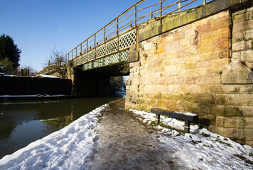Icy canal towpath leading under a railway bridge