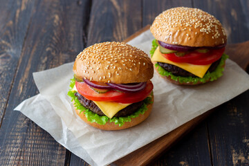 Burgers with cutlet, tomato, lettuce, cucumber, onion and cheese. American cuisine. Fast food. Cheeseburger.