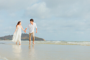 Fototapeta na wymiar Love young couple holding hands and running on the beach. Holiday and vocation concept.
