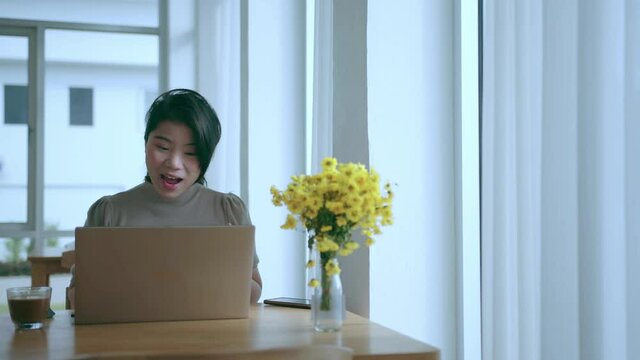 attractive asian female use laptop working online conference meeting social distancing new normal working lifestyle,asian woman working near big glass window morning time