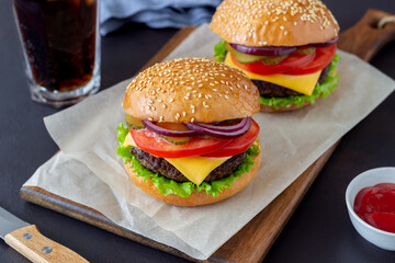 Burgers with cutlet, tomato, lettuce, cucumber, onion and cheese. American cuisine. Fast food. Cheeseburger.