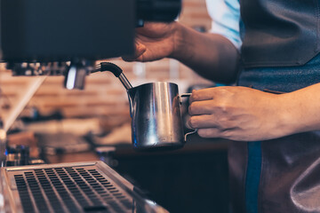 Fototapeta na wymiar Barista heats milk steam for making lattes at coffee shop.