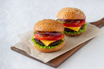 Burgers with cutlet, tomato, lettuce, cucumber, onion and cheese. American cuisine. Fast food. Cheeseburger.