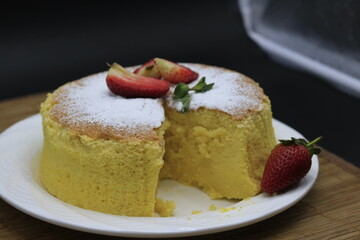 Cheesecake decorated with icing sugar, mint and strawberry in a white plate