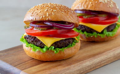 Burgers with cutlet, tomato, lettuce, cucumber, onion and cheese. American cuisine. Fast food. Cheeseburger.