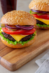 Burgers with cutlet, tomato, lettuce, cucumber, onion and cheese. American cuisine. Fast food. Cheeseburger.