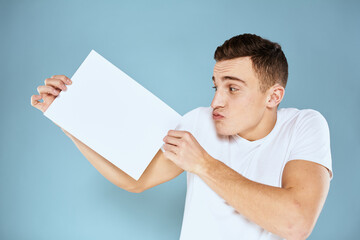 man holding a sheet of paper in his hands white t-shirt cropped view blue background