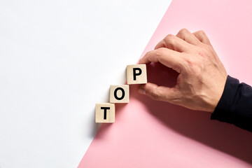 Male hand arranging the wooden cubes with the word top. Climbing or reaching to the top in business or career