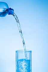 Pure water is poured into a glass. Clear water in a glass on a blue background.