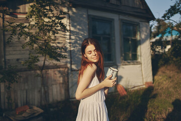 happy woman near building with iron mug outdoors in garden