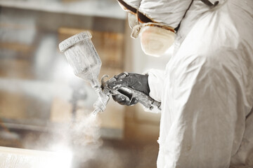 Man working with paint spray gun, airless spraying to wood