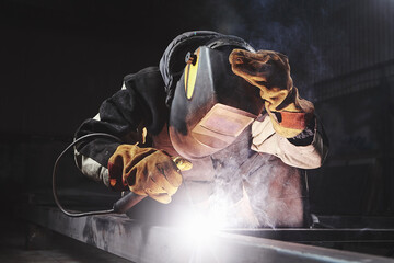 Male in face mask welds with welding