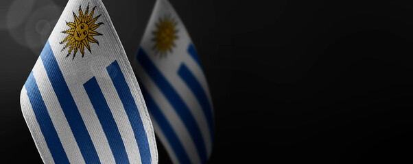 Small national flags of the Uruguay on a dark background