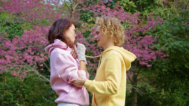 Homosexual lesbian couple hugging in a sakura garden. Two women share love and support while holding hands. Gay Family. LGBT concept of friendship. cinematic chot bmpcc 6k