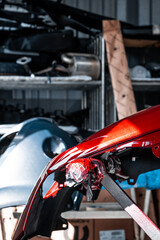 Closeup shot of the disassembled vehicle. Professional paint job. New shiny red color, car repair service, maintenance facility, garage. Glossy details, sharp image. Industrial and occupation concept.