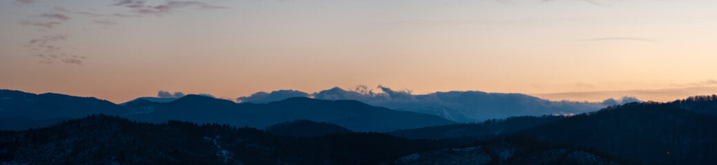 Panorama of the silhouette of mountains and forest on the background of sunset