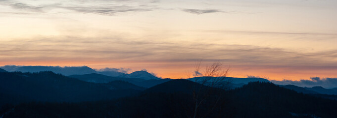 Panorama of the silhouette of mountains and forest on the background of sunset