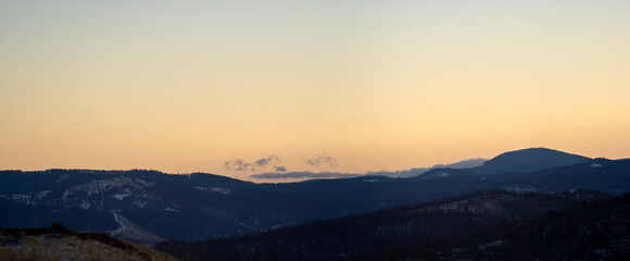 Panorama of the silhouette of mountains and forest on the background of sunset