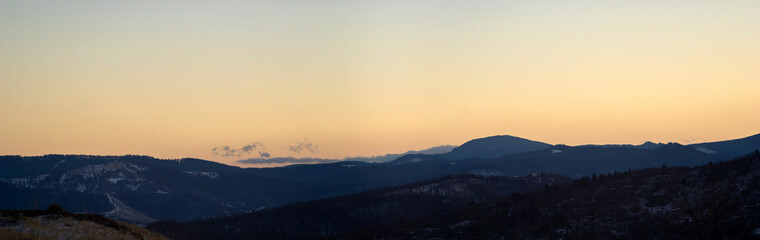 Panorama of the silhouette of mountains and forest on the background of sunset