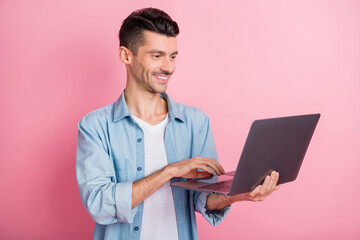 Photo portrait young entrepreneur working on laptop smiling typing texting browsing internet isolated pastel pink color background
