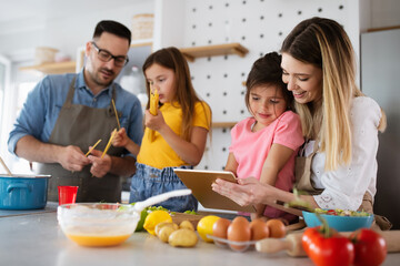 Overjoyed young family with kids having fun, cooking at home together