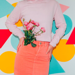 Model in pink clothes holds spring flower bouquet on colorful background. Modern creative...