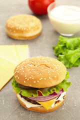Homemade burger ingredients arranged on grey background
