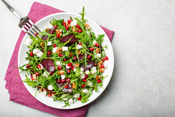 Beet salad with arugula, feta cheese, walnuts and pomegranate fruit.