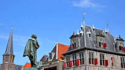 Close-up on the statue of Jan Pieterszoon Coen (1587, 1629), historic houses and the tower of Grote...