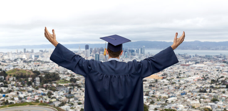 Education, Graduation And People Concept - Happy Male Graduate Student In Mortar Board And Bachelor Gown Celebrating Success From Back Over Singapore City Background