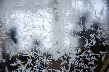 Frosty pattern on glass. Snowy frosty texture on a glass surface. Frost on the glass of the window. Frosty window. Snowflakes on the glass in winter.