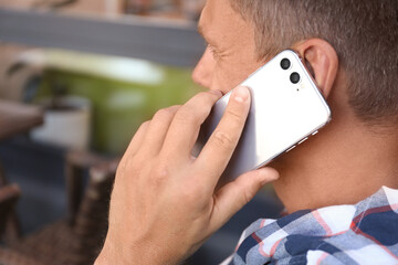 Man talking on smartphone in outdoor cafe, closeup
