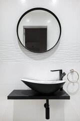White tiled bathroom with black faucet and basin and round mirror. Modern and minimalist style