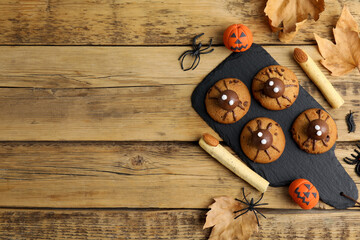 Delicious cookies decorated as monsters on wooden table, flat lay with space for text. Halloween treat
