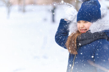 child girl playing with snow in winter outdoor and having fun on snowy winter